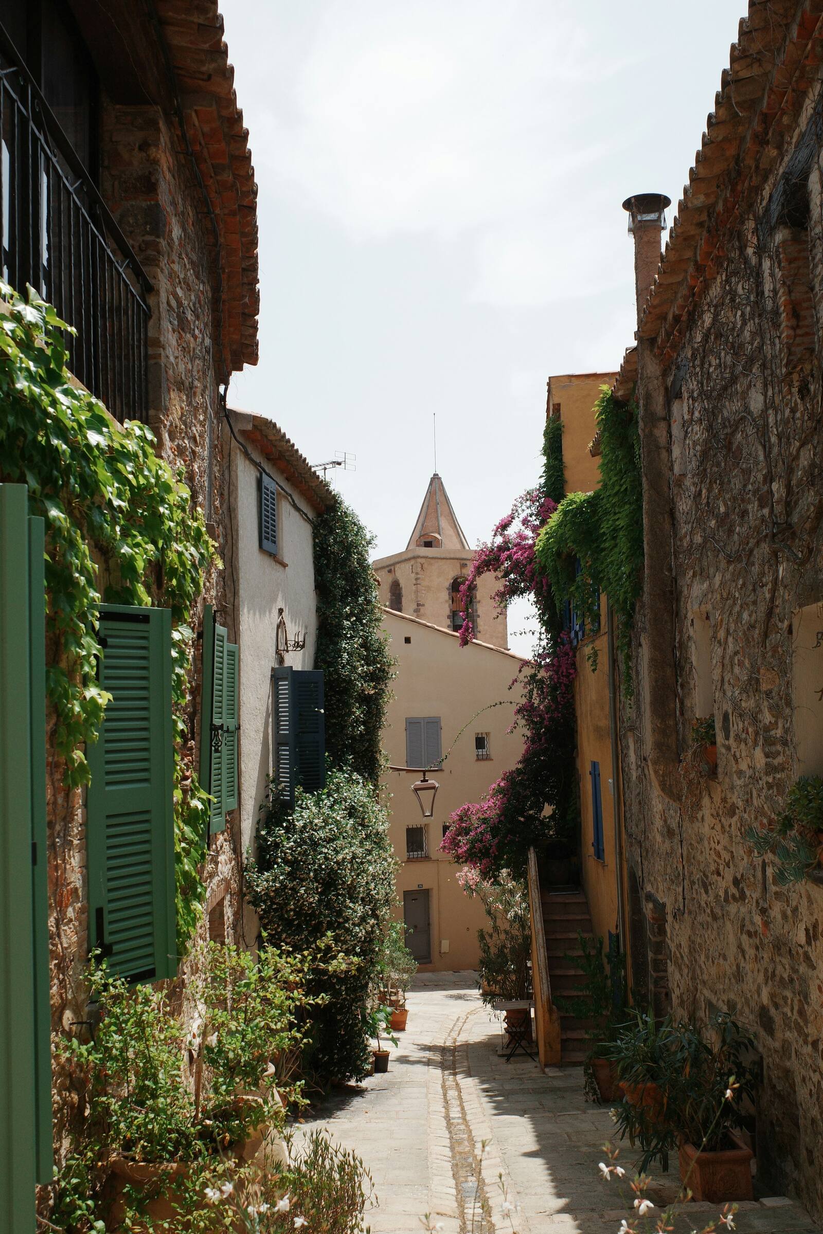 Eine blumengeschmückte Gasse in einem provenzalischen Dorf, mit Kirchturm